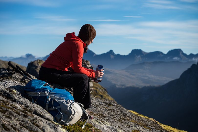 Female hiker takes a break and enjoys mountain views, Moskenesøy, Lofoten Islands, Norway