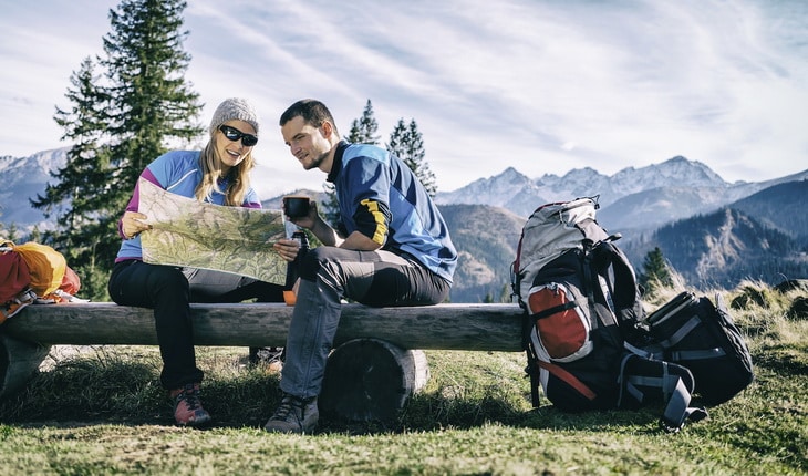 Couple hikers with map in mountains
