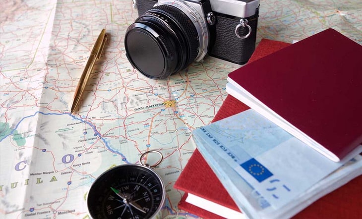 A camera, a compass, agenda and a pen on a map