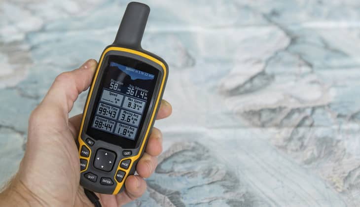 Hand held outdoor GPS and a hiking map of a mountain range.