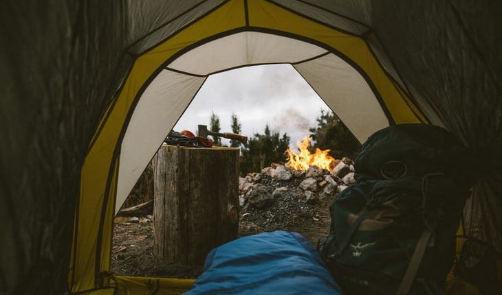 Person in a sleeping bag in tent looking outside