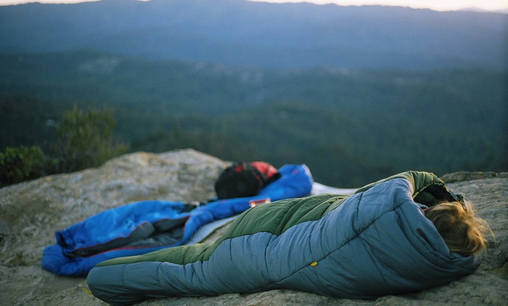 Person in a sleeping bag on top of the mountains