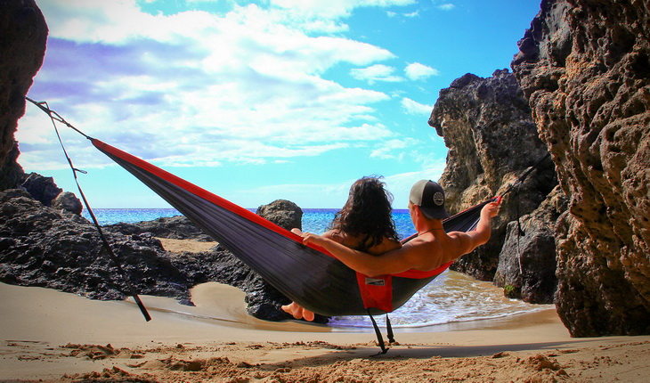 A couple relaxing in a ENO Eagles Nest Outfitters - DoubleNest Hammock and watching the Ocean