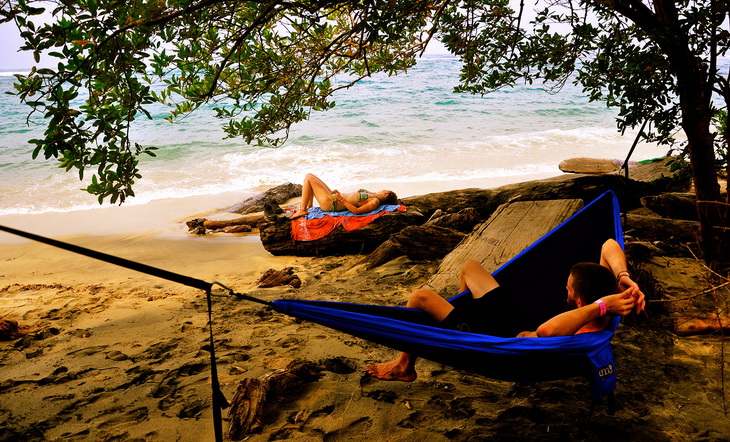 A man sitting in a Woman relaxing in a ENO Eagles Nest Outfitters - DoubleNest Hammock and watching the Ocean