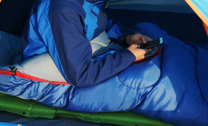 Man in a sleeping bag checking the phone