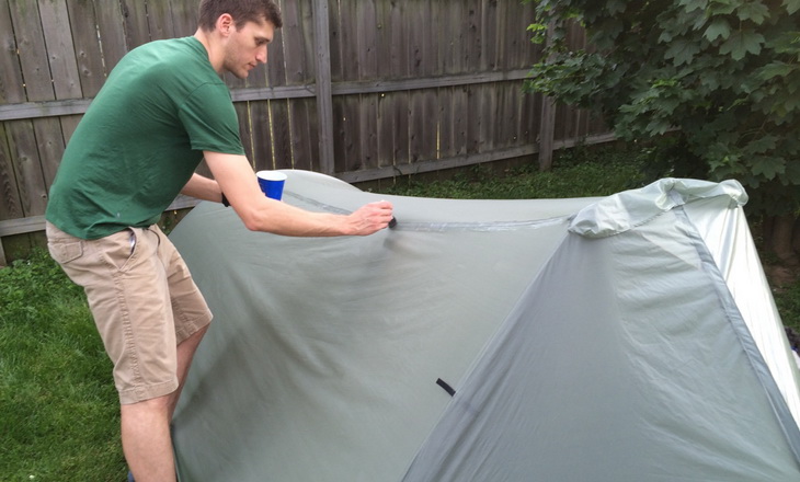 A man seam sealing his tent