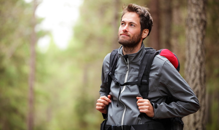man hiking in forest wearing a fleece jacket