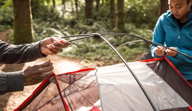 Two persons embeding tent poles