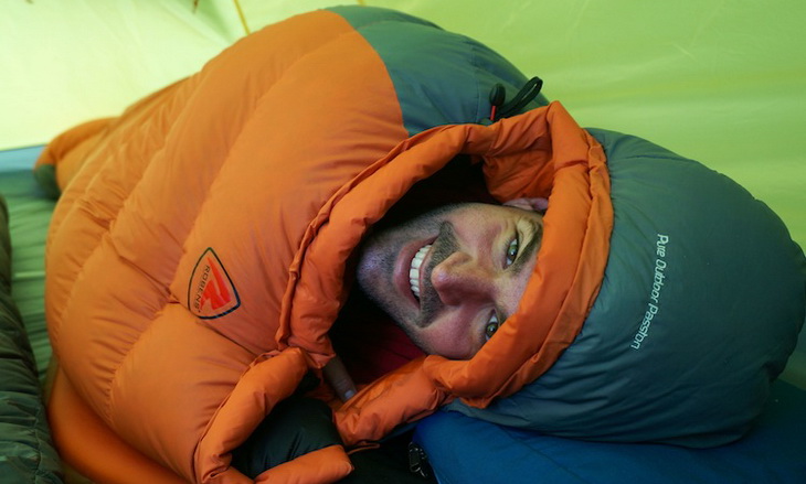 Man in a sleeping bag smiling at the camera