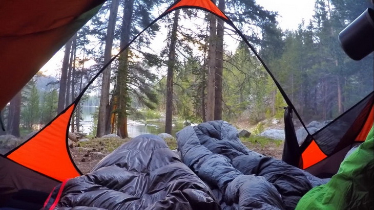 Two adults in Nemo sleeping bags looking at a lake