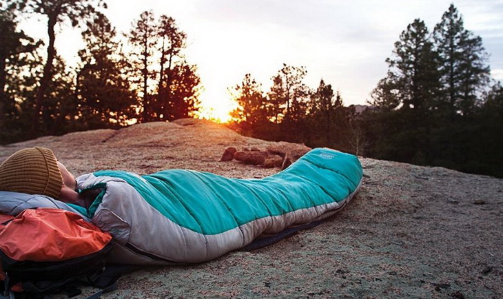The man is lying in a sleeping bag