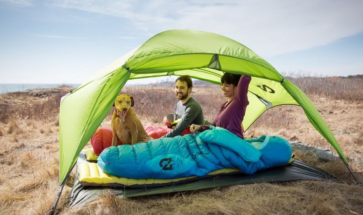 A couple camping in the wilderness with their dog 