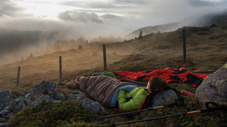 woman in a sleeping bag watching the sunset