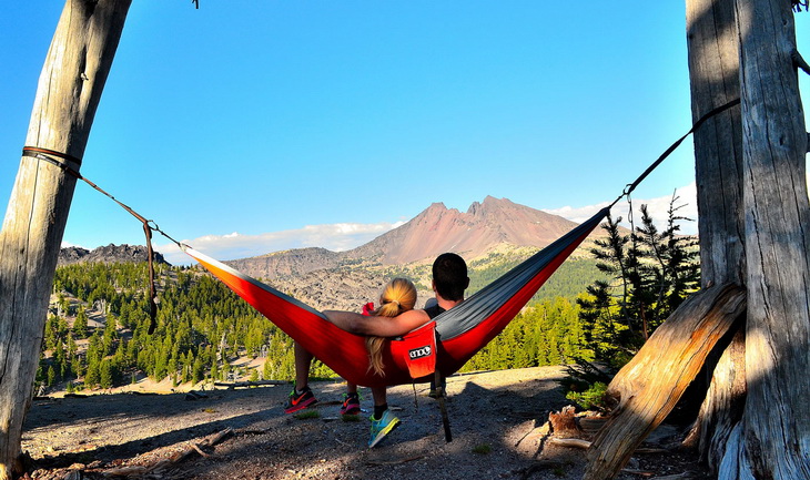Couple relaxing in Eagles Nest Outfitters DoubleNest hammock and looking at the mountain
