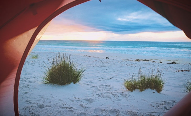 Person Inside Tent Watching Shore Line View during Sunset