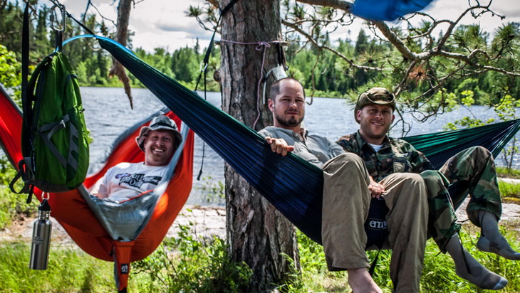 3 adults sitting in Eagles Nest Outfitters DoubleNest hammock outside in the wild