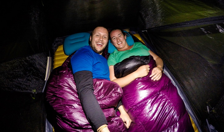 A couple in a tent sitting in Western Mountaineering Highlite Sleeping Bags