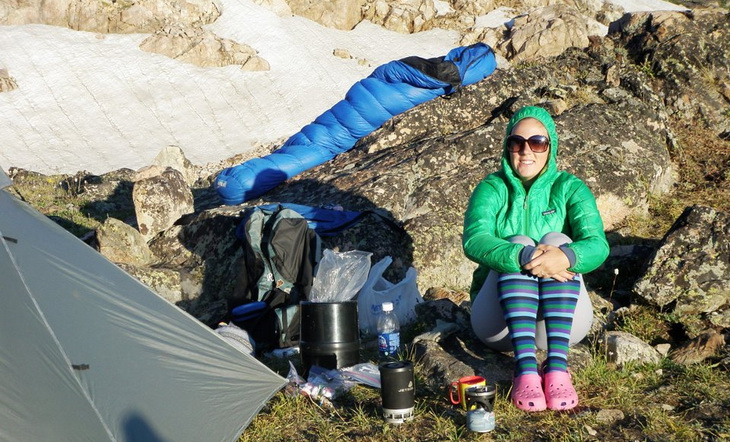 A woman looking at the camera and a sleeping bag at her back