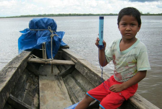 kid holding a lifestraw in boat