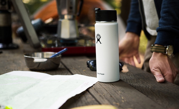 A Vacuum-Insulated-Water-Bottle on a Table next to a manA Vacuum-Insulated-Water-Bottle on a Table next to a man