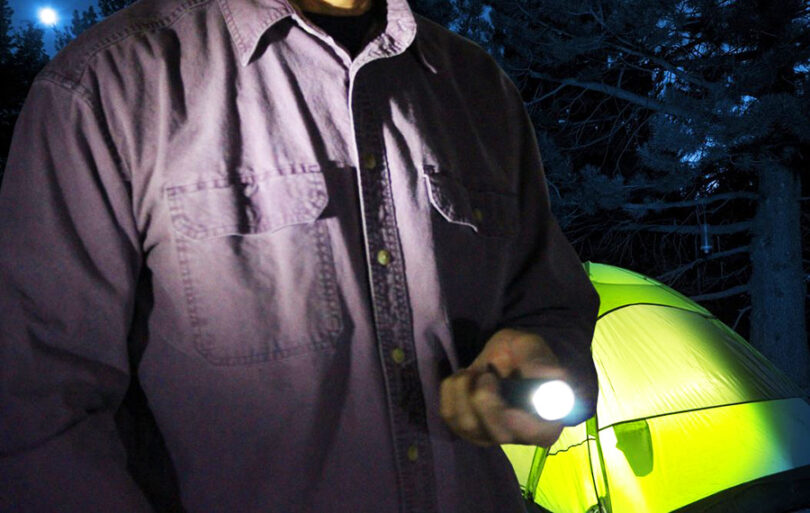 camper holding tactical flashlight
