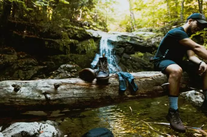 hiker sitting on a tree with hiking and backpacking boots