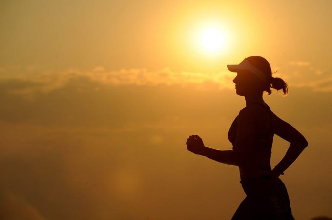 A woman jogger running on sunset