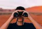 young man looking trough compact binoculars