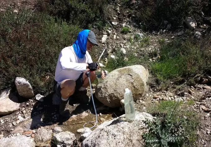 hiker filling water bottle