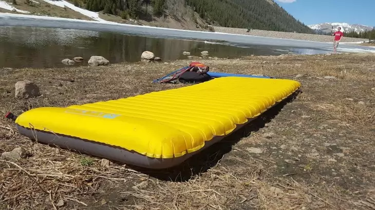 Backpacking-sleeping-pad on the ground near a water