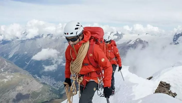 A man climbing the mountains wearing a hardshell jacket to keep his warm