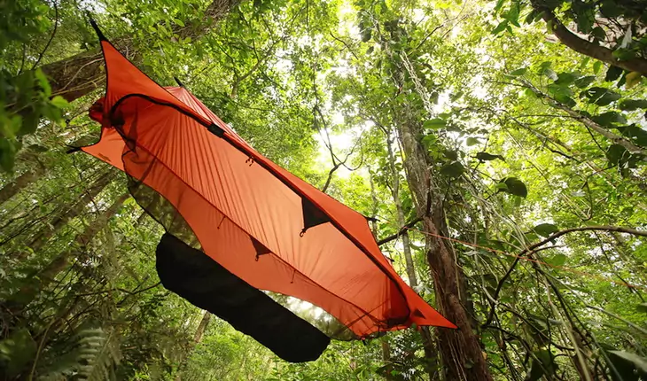Orange tent hammock hanging in the forest