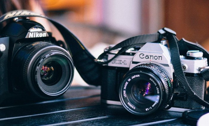 Canon photo camera next to a Nikon camera