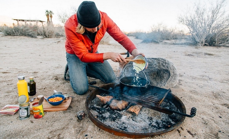 A man cooking a meal in outside in the camp