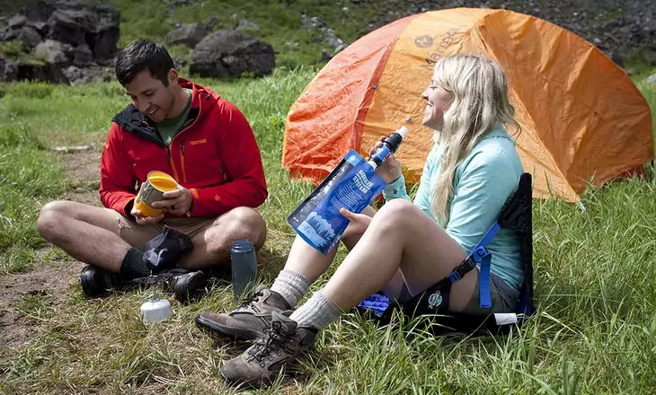 A woman drinking water from a backpacking filter