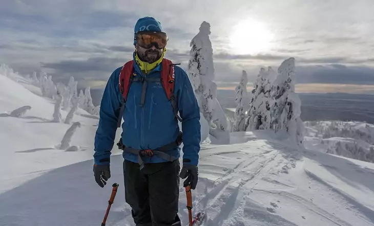 A man wearing hardshell jacket is climbing the mountains