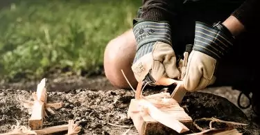 man wearing gloves starting a fire