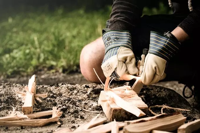 man wearing gloves starting a fire