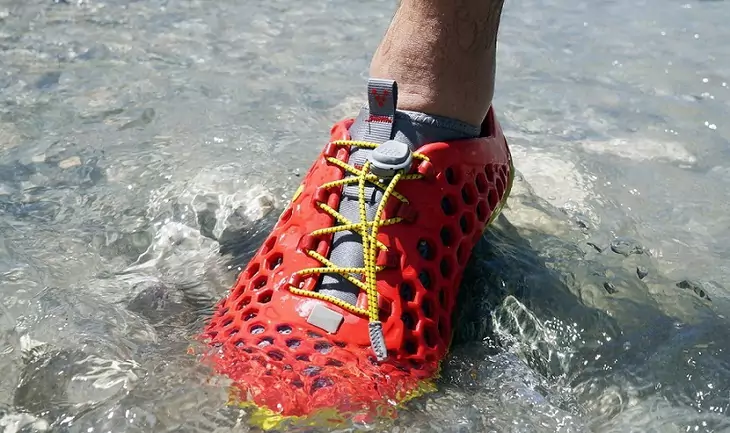 A man stepping into water wearing a pair of water shoes