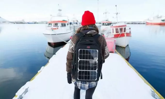 A woman with a solar backpack sitting in a port