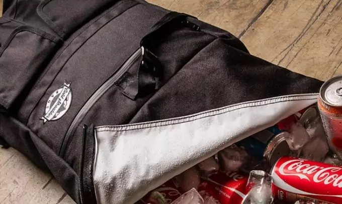A cooler bag full of coca cola on the floor