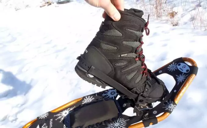 A person holding a pair of snowshoeing boots