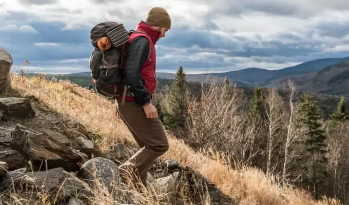 A hiker with a backpack going down on a moutain