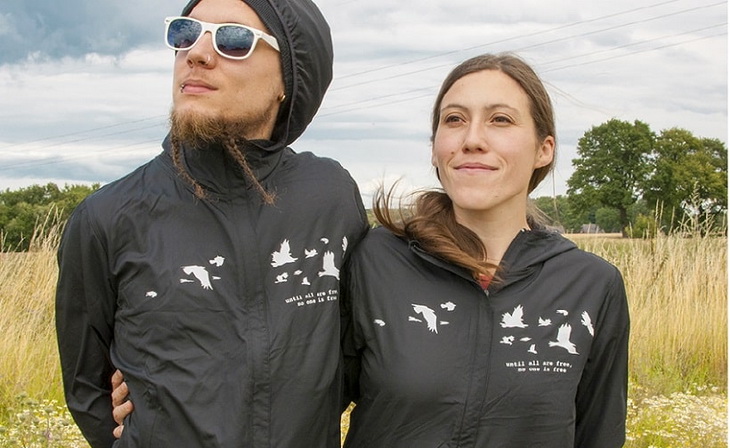 Two adults wearing windbreaker jackets sitting outside in the wind