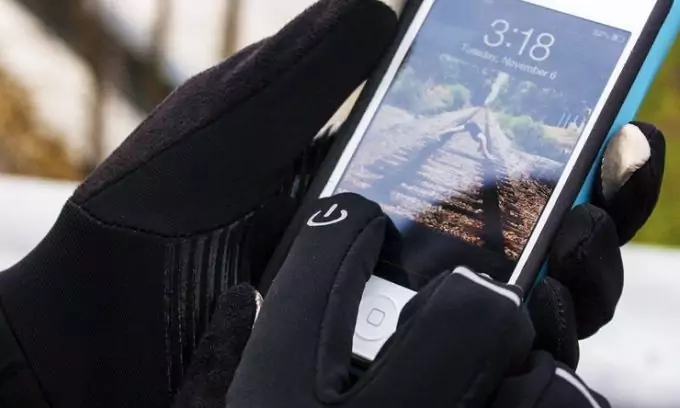 A man weaaring a pair of winter gloves alos used for touchscreen of the smarphone