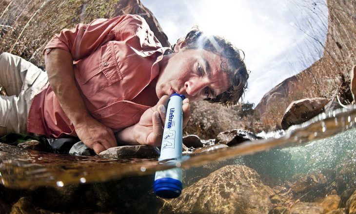 A man drinking water with a Lifestraw Water Filter