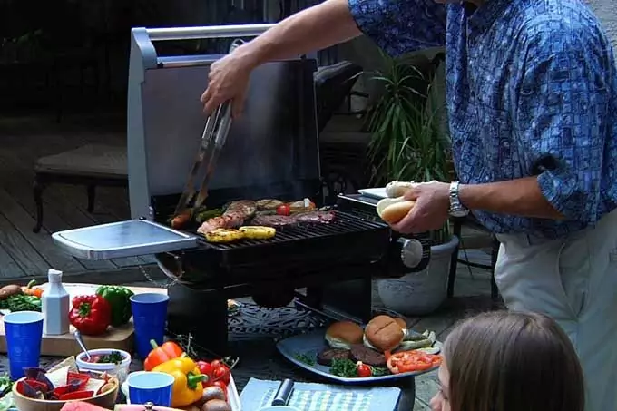 man cooking on portable gas grill