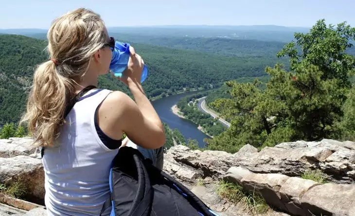A woman hiker drinking water from a water bottle