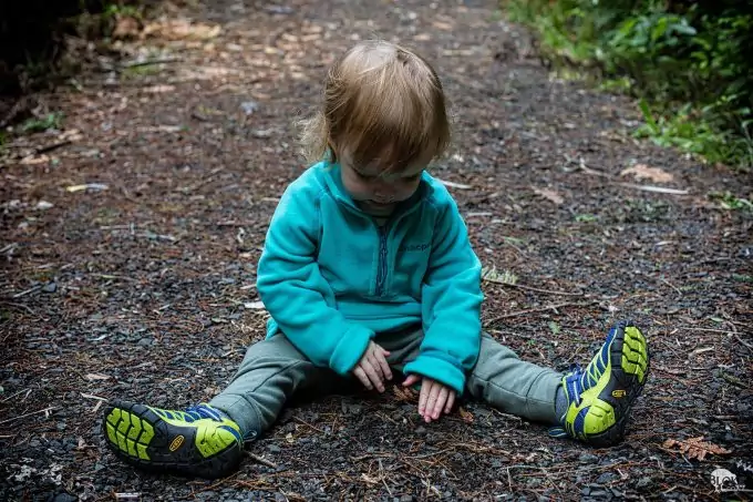 child sitting on ground with hiking shoes