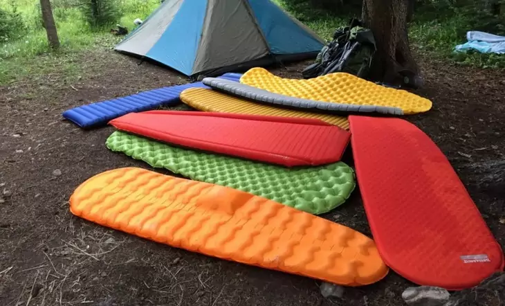 Ultralight sleeping pads on the ground near a tent in the forest